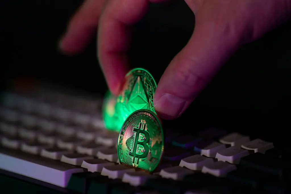Hand hält eine Bitcoin-Münze über einer Computertastatur – Symbolbild für digitale Erpressung, Kryptowährungszahlungen und Ransomware-Bedrohungen im IT-Kontext.